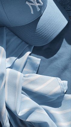 a baseball cap laying on top of a blue and white shirt next to another hat