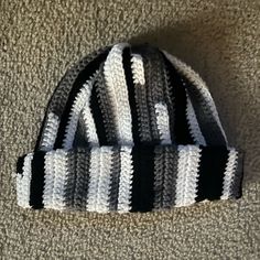 a black and white striped hat laying on top of a carpeted floor next to a wall