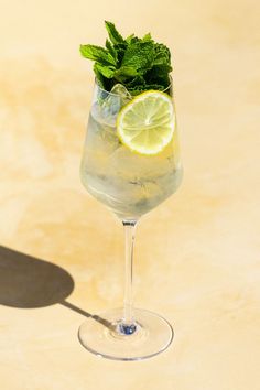 a glass filled with ice and lemon on top of a table next to a shadow