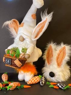 two stuffed animals sitting next to each other with carrots on the ground in front of them