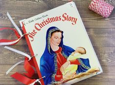 a christmas story book with a red ribbon around it and a spool of yarn next to it