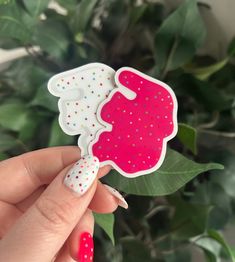 a hand holding up a pink and white sticker with polka dots on it's side