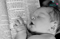 a baby laying on top of an open book with its head resting on it's hand