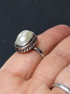 ► ABOUT THIS RING This is a vintage sterling silver statement ring with 1 off-white imitation Pearl. Wonderful craftsmanship. The front of the ring is 18x14mm. The ring band is 2.5mm wide. Our family acquired this ring around 1996, as part of a large jewelry collection. It's in great condition, unworn, antiqued and may be tarnished. It's been in storage all of these years. This ring would make a nice addition to any collection of beautiful heirloom jewelry. ► MORE FROM THIS SHOP See our other pe Vintage Pearl Ring With Gemstone, White Open Ring Stamped 925, White Stamped 925 Open Ring, Classic Adjustable Oval Pearl Ring, Classic White Cabochon Moonstone Ring, Vintage Handmade White Pearl Ring, Handmade Vintage Pearl Ring In Sterling Silver, Elegant White Crystal Ring Stamped 925, Classic White Moonstone Open Ring