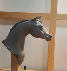 a statue of a horse is on display in a room with wood framing and white walls