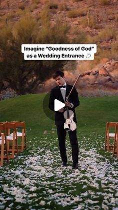 a man in a tuxedo is holding a violin and looking down at the ground