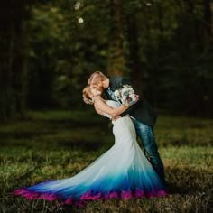 a bride and groom kissing in the woods