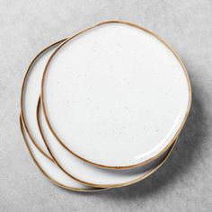 three white plates with gold rims are stacked on top of each other, one is empty