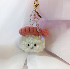 a small stuffed animal with a pink hat on it's head hanging from a chain