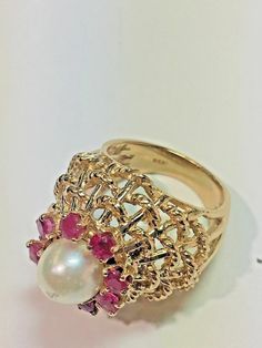 Vintage 14k Yellow Gold Dome White Pearl Red Ruby Domed Basket Weave Ring Size 5 Metal: 14k yellow gold, stamped Stones: (8) Natural Rubies measuring 2.5mm each, (1) Natural White Pearl Measuring 7.5mm with slight wear on top of the pearl Ring Size: 5 (can be resized upon request) Size: Sits 17mm high off the finger, Center cluster measures 15mm in diameter, 20mm wide (north to south) Hallmarked: 14k Textured rope design details on the basket This is an estate piece in very good condition. Pleas Fine Jewelry Yellow Gold Ruby Ring With Intricate Design, 14k Yellow Gold Ruby Ring With Intricate Design, Fine Jewelry Red Ruby Ring With Intricate Design, Exquisite Multi-stone Yellow Gold Ruby Ring, Gold Ruby Ring With Diamond Cut, Exquisite 14k Gold Red Rings, Exquisite 14k Gold Ruby Ring, Gold Ruby Ring With Intricate Design, Fine Jewelry Gold Ruby Ring With Intricate Design