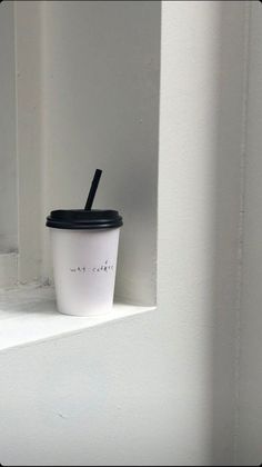 a coffee cup sitting on top of a window sill with a straw in it