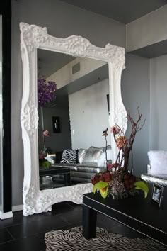 a large white mirror sitting on top of a wooden table next to a black and white rug