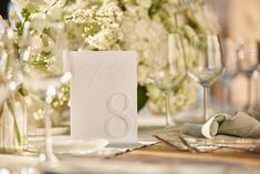 the table is set with wine glasses, napkins and place cards for an elegant wedding reception