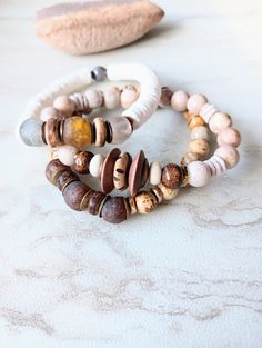 Soft, serene, cozy, and beachy. Beautiful beige, white, caramel, brown, and ecru in these mixed medium stack bracelets. Several creamy Fossilized Coral, and Picture Jasper gemstone beads in different sizes and colors. Large ethical bone beads, matte sea shells dyed in a soft white, natural coconut disk beads, rustic antique beads, and African recycled glass. Mix in with an array of mixed metals, and cluster accents of mixed gemstone beads including pearls. Unique and stunning. The item/s picture Brown Natural Stone Beaded Bracelets For Beach, Brown Beaded Bracelets With Natural Stones For Beach, Brown Natural Stones Beaded Bracelets For Beach, White Bohemian Stackable Bracelets, Everyday Hand Wrapped Brown Bracelets, Everyday Brown Hand-wrapped Bracelets, Bohemian White Bracelets For Everyday, Bohemian White Stackable Bracelets, Everyday Brown Hand Wrapped Bracelets