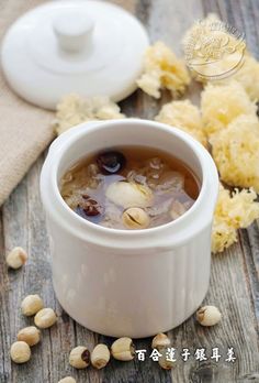 a bowl filled with soup sitting on top of a wooden table next to some nuts