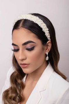 a woman wearing a white headband with pearls on the side and long hair in front