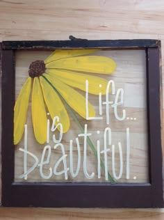 a wooden sign that says life is beautiful with a yellow flower in the center and words below it