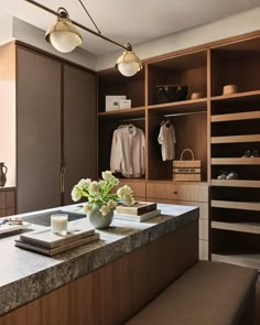 a kitchen counter with flowers and candles on it in front of a closet full of clothes