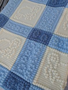 a blue and white crocheted blanket sitting on top of a bed