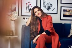 a woman sitting on top of a blue couch in a living room next to pictures