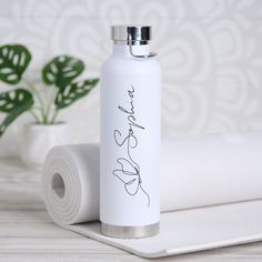 a white water bottle sitting on top of a table next to a roll of toilet paper