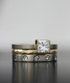 two wedding bands with a square diamond in the middle and round diamonds on each band