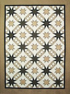 a black and white quilt is hanging on the wall in front of a beige background