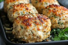 some meatballs on a black plate with parsley and seasoning sprigs