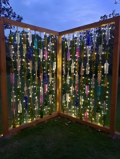 a fence made out of wine bottles with lights on it and some grass in the foreground