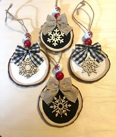 four ornaments are hanging on the table with snowflakes and ribbon around them