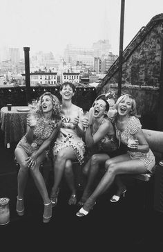 four women sitting on a bench with their mouths open and one woman laughing at the camera