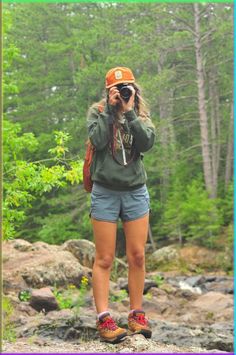 a woman standing on top of a rock while taking a photo with her cell phone