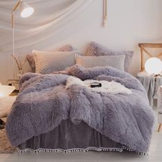 a bed covered in purple fluffy blankets and pillows