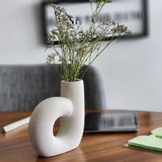 a vase with flowers in it sitting on a table next to a book and pen