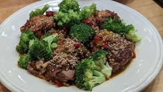 a white plate topped with meat and broccoli on top of a wooden table