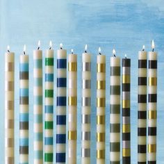 five candles lined up next to each other with different colors on them in front of a blue background