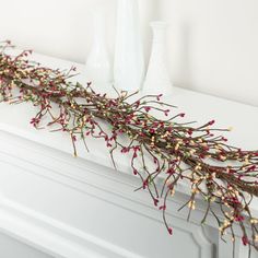 a white fireplace mantel topped with branches and flowers