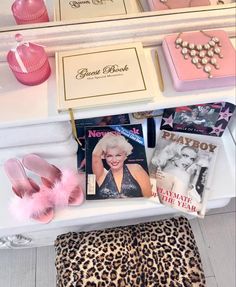 some pink and gold items are sitting on a white shelf next to a leopard print ottoman