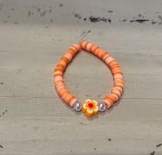 This listing is for one handmade bracelet with various shades of orange and light peach. It also has two small pearl-like beads on either side of an orange flower bead.**SHIPPING INCLUDED** This bracelet is offered in three sizes. Please check the Sizing Guide carefully before ordering. Ages listed are approximate. Please measure before ordering. We do not offer returns, but please email if you are not fully satisfied.  **SIZING GUIDE** Little Kid (Ages 5-7) Bracelet length is 5.75" long. Big Kid (Ages 8-11) Bracelet length is 6.25" long. Standard (Ages 12+) Bracelet length is 6.75" long.  Our bracelets are triple-knotted, but should not be overstretched. CHOKING HAZARD for young children. All of our bracelets arrive nicely packaged. Please let us know if you'd like to include a free, hand Orange Flower Jewelry For Beach, Orange Flower-shaped Jewelry For Beach, Orange Flower-shaped Beach Jewelry, Orange Flower Bracelet For Gift, Handmade Adjustable Peach Bracelets, Orange Flower-shaped Beaded Bracelets For Gifts, Flower-shaped Orange Beaded Bracelets For Gifts, Adjustable Orange Flower-shaped Beaded Bracelets, Orange Flower