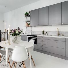 a white table and chairs in a room with stainless steel cabinets, marble counter tops and open shelves