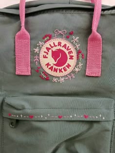 a green bag with pink handles and embroidered logo