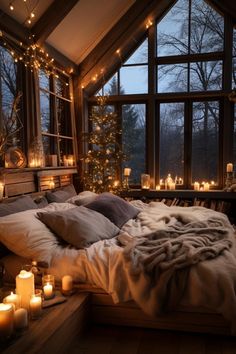 a cozy bedroom with candles lit up in the window, and a bed covered in blankets