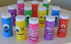 there are many different colored water bottles with faces painted on them and one is empty