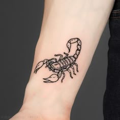 a small scorpion tattoo on the wrist