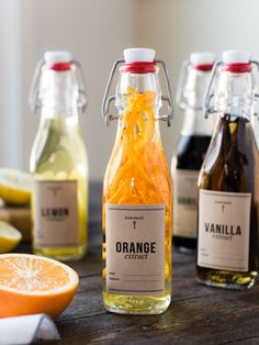 three bottles of orange juice on a table with sliced lemons and grapefruit