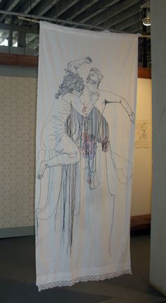 a white banner hanging from the ceiling in front of a wall with drawings on it