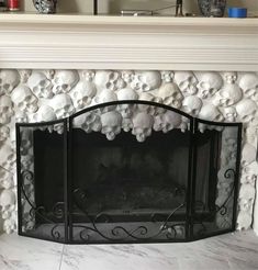 a fireplace with skulls on the mantle and fire in the middle is decorated with white marble