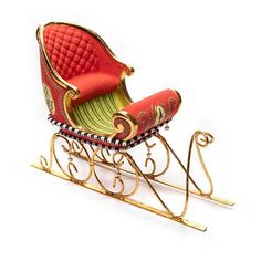 a red and green miniature sleigh with gold trimmings on the sides