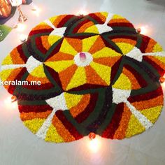 a colorful flower design on the floor with lights around it and candles in the background