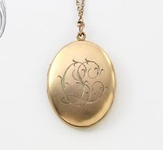 "A fantastic large-sized antique yellow gold-filled locket with a bloomed finish and applied Etruscan style wire-work filigree decoration. The filigree pattern is reminiscent of a William Morris print with its gracefully exuberant arrangement of scrolls framing the stone. The back has been engraved with the initials \"C.L.\" in rich foliate ribbon script. Measuring approximately locket 1 5/8\" inches north to south and 1 1/4\" east to west; the locket opens to reveal a gilded interior with space Victorian Filigree Yellow Gold Locket Necklace, Victorian Filigree Locket Necklace In Yellow Gold, Victorian Yellow Gold Locket Necklace With Filigree, Heirloom Filigree Locket Pendant Necklace, Victorian Filigree Medallion Locket Necklace, Victorian Medallion Locket Necklace With Filigree, Victorian Style Filigree Medallion Locket Necklace, Victorian Style Medallion Locket Necklace With Filigree, Victorian Yellow Gold Locket Necklace For Formal Occasions